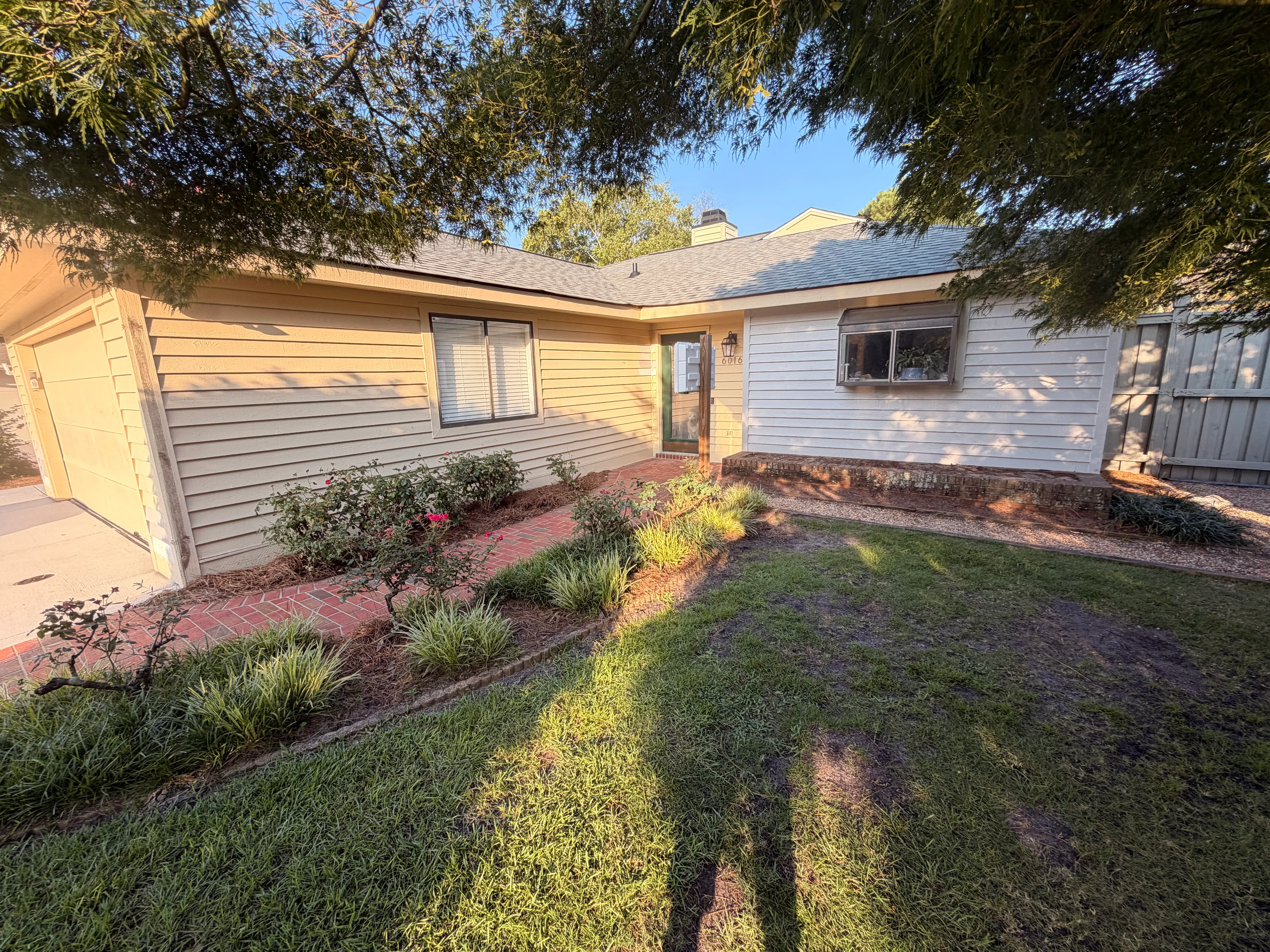 Pressure-washed single-story home with clean horizontal siding, brick driveway, and landscaped yard