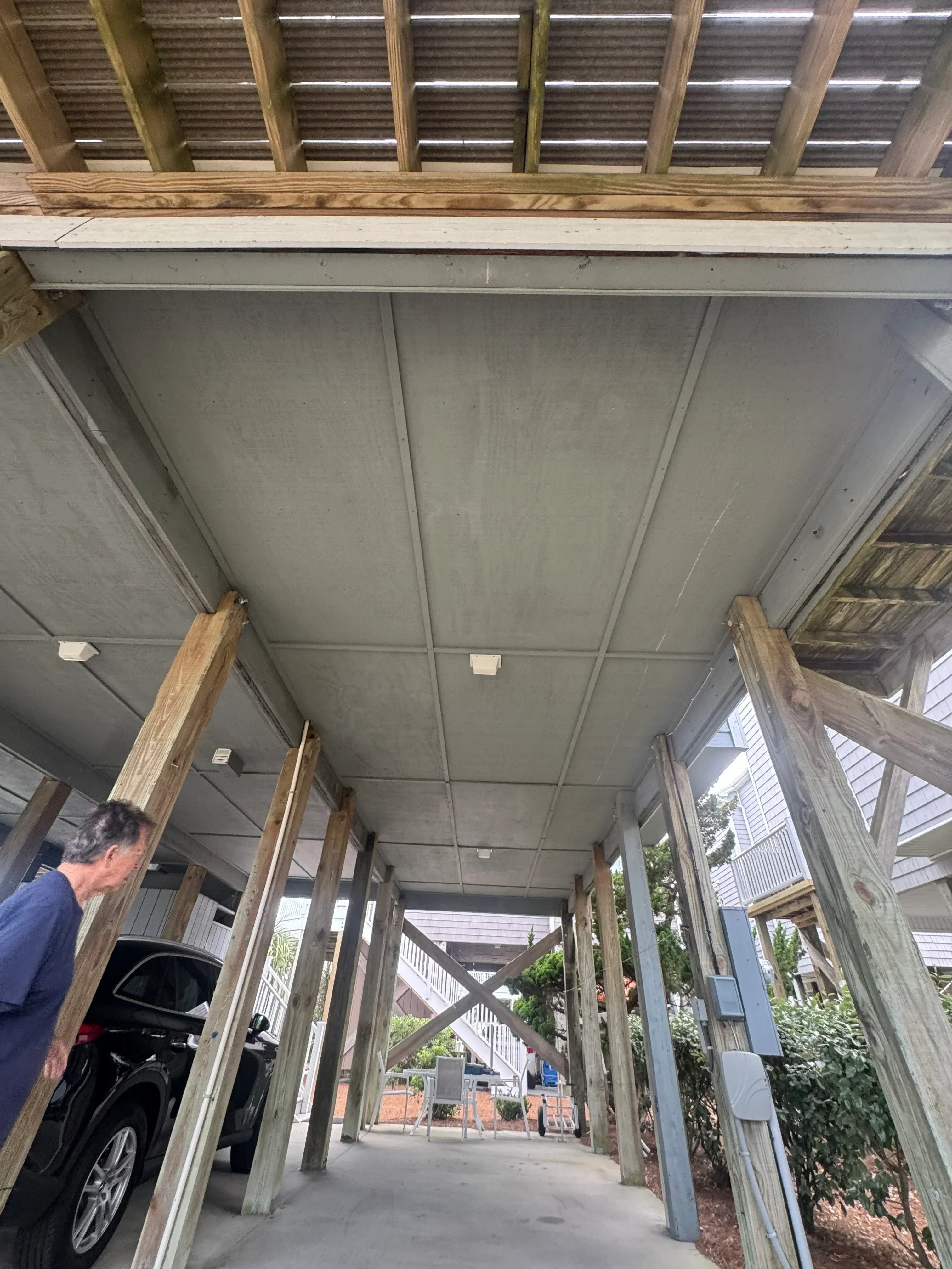 Timber pergola with corrugated metal roof and wooden beam framing over garage