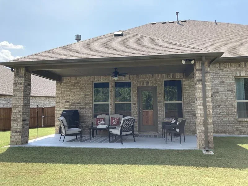 Brick covered patio with concrete pad, pitched roof, and French doors