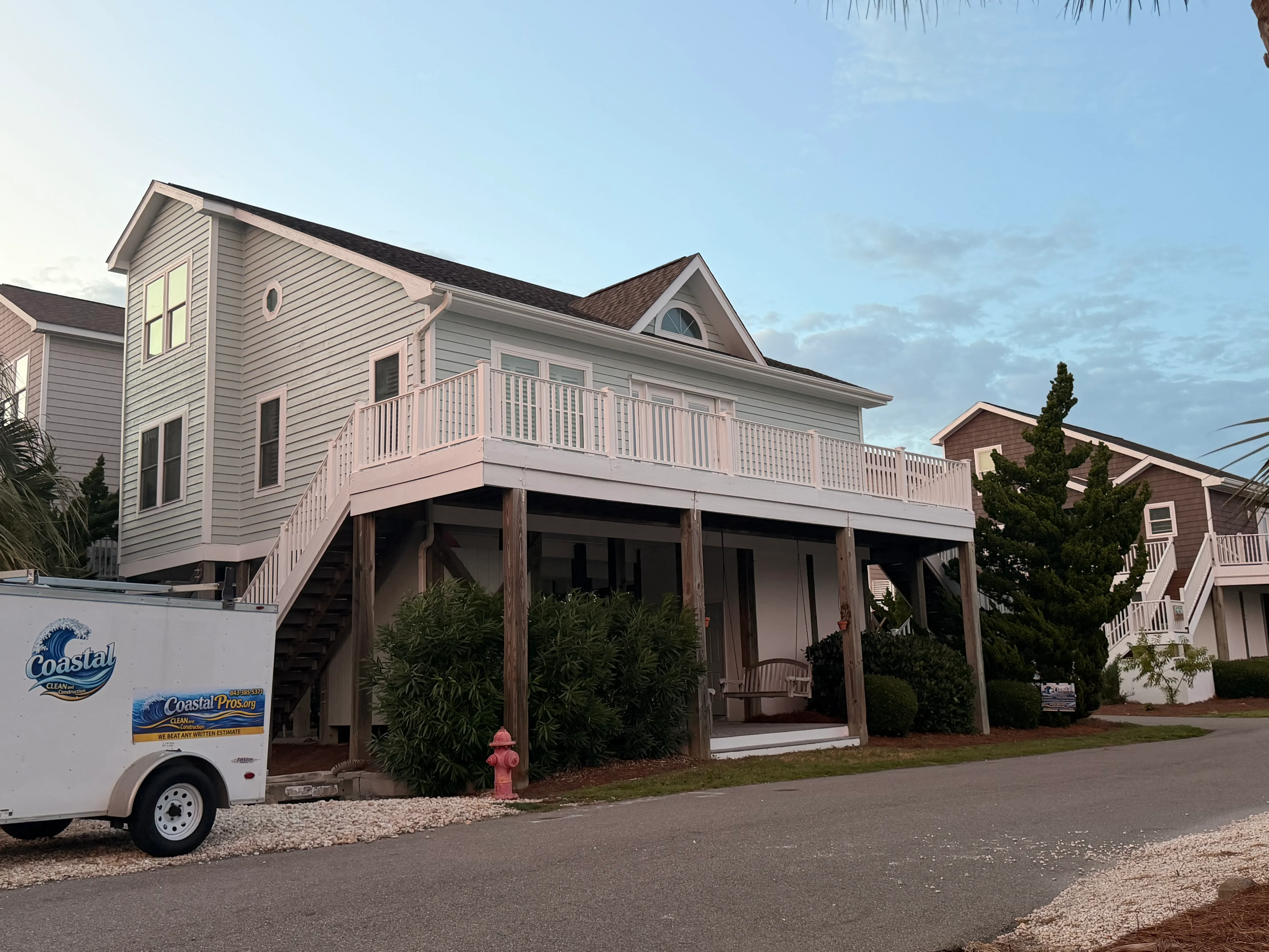Elevated coastal home with white vinyl railing deck and wooden support posts