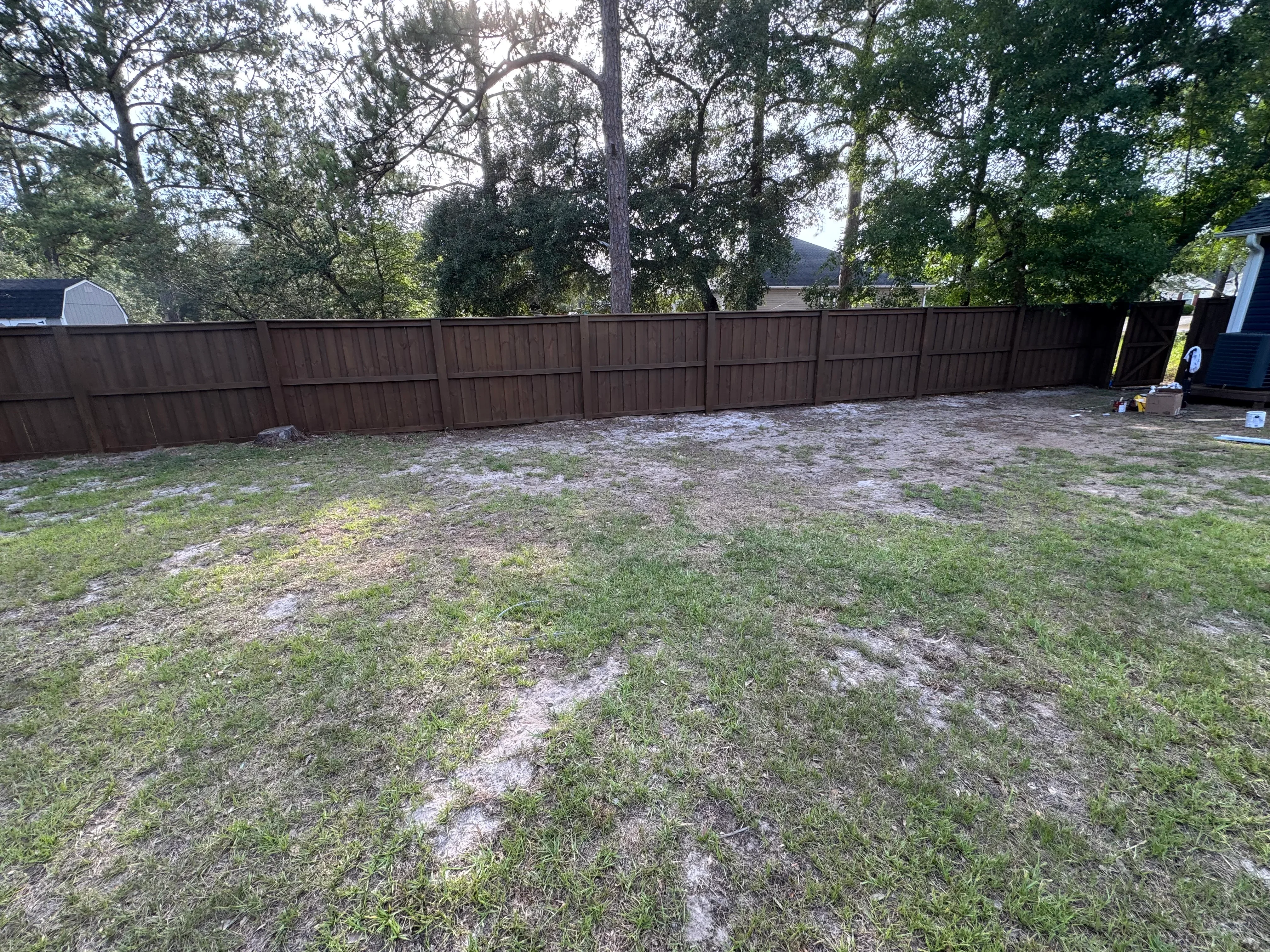 Brown vinyl privacy fence with vertical boards installed in residential backyard