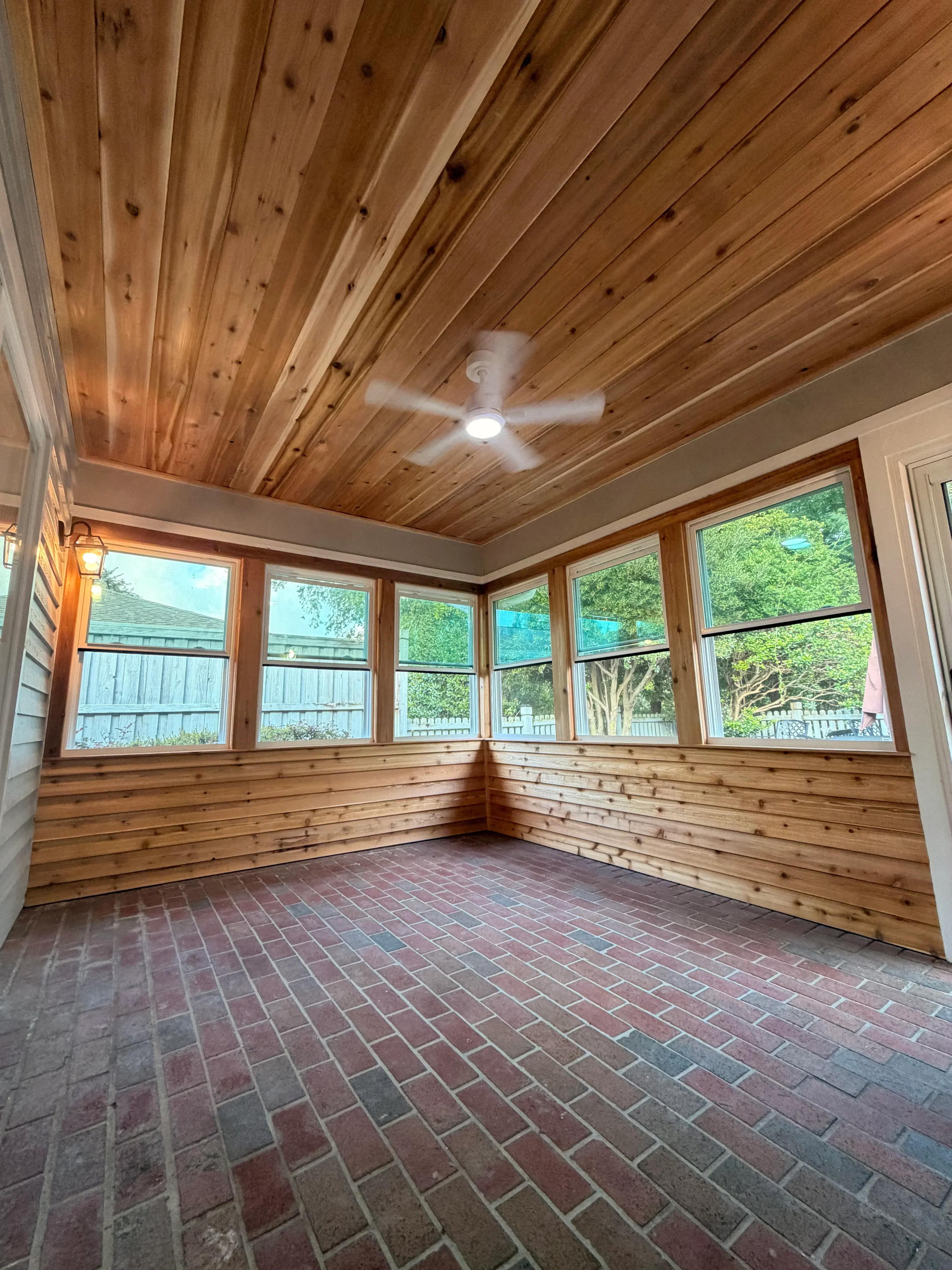 Vertical cedar wood paneling sunroom with multi-pane skylight and ceiling fan